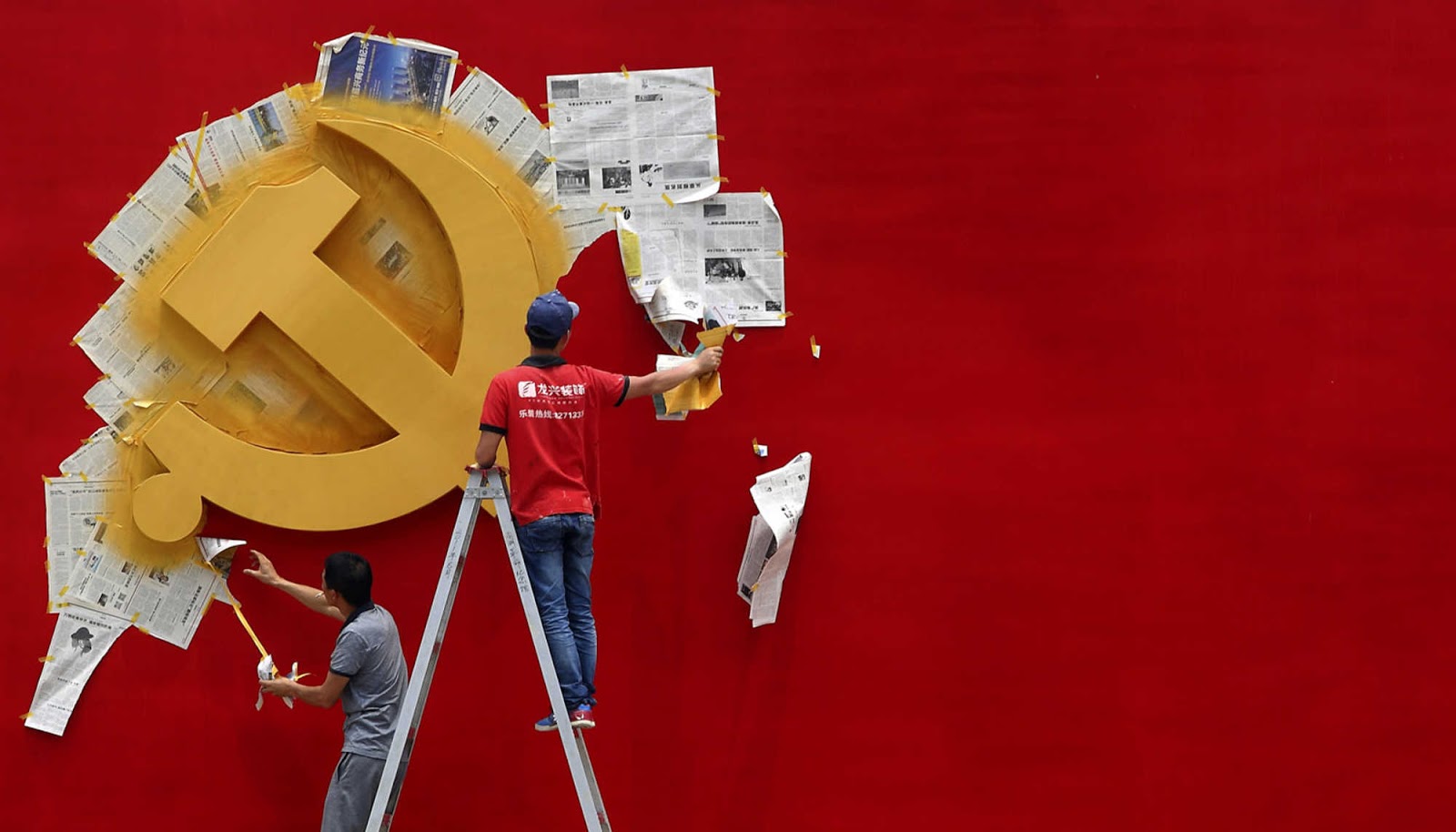 Workers peel papers off a wall as they re-paint the Chinese Communist Party flag on it at the Nanhu revolution memorial museum in Jiaxing, Zhejiang province May 21, 2014. REUTERS/Chance Chan