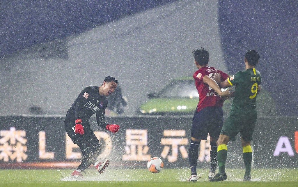 Beijing Guo'an and Chongqing of CSL playing on a rainy waterlogged pitch in Suzhou