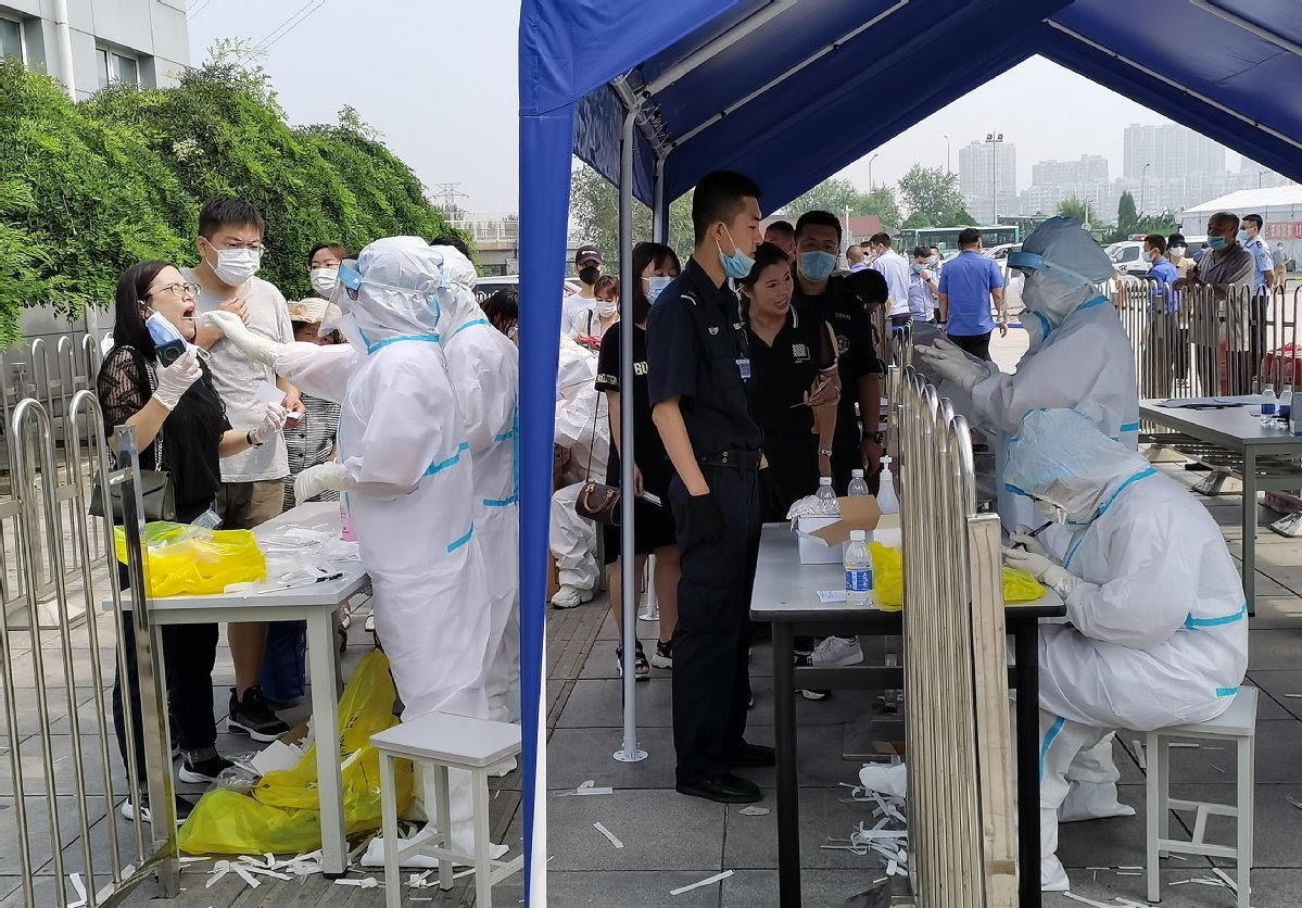 a medical worker wearing PPE gives a throat swab to a chinese person in dalian, china to test for covid-19