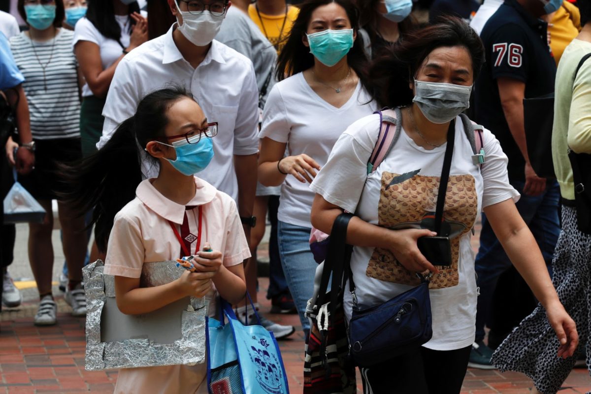 a student in hong kong wears a surgical mask in a crowd of people