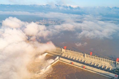 an aerial photo of the three gorges dam in china discharging water, with clouds above