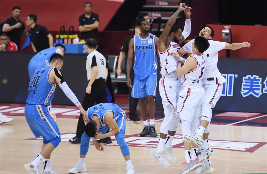 Beijing player hunches over while Guangdong celebrates making the CBA finals
