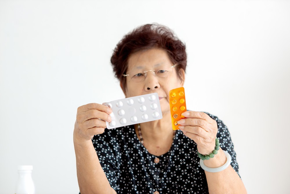 elderly asian woman holding pharmacy prescription