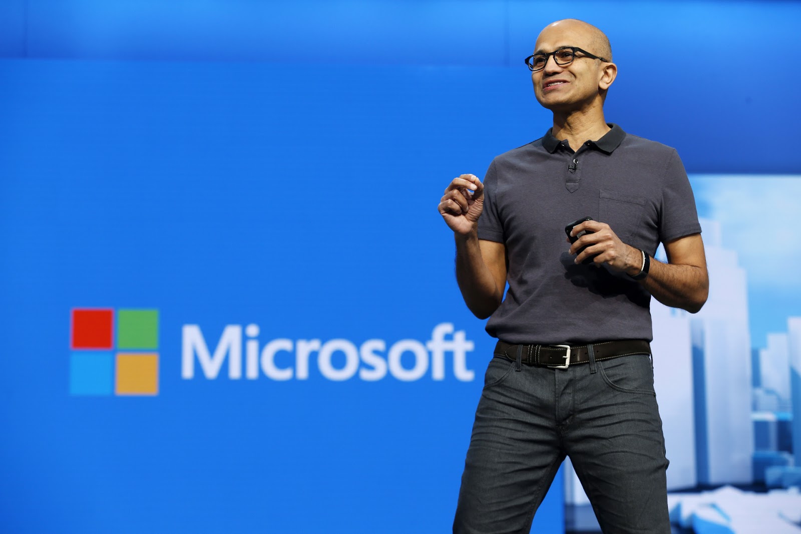 microsoft ceo satya nadella standing in front of a microsoft logo