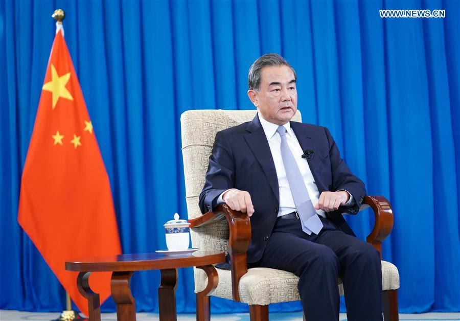 Chinese foreign minister Wang Yi sitting, next to a flag of China