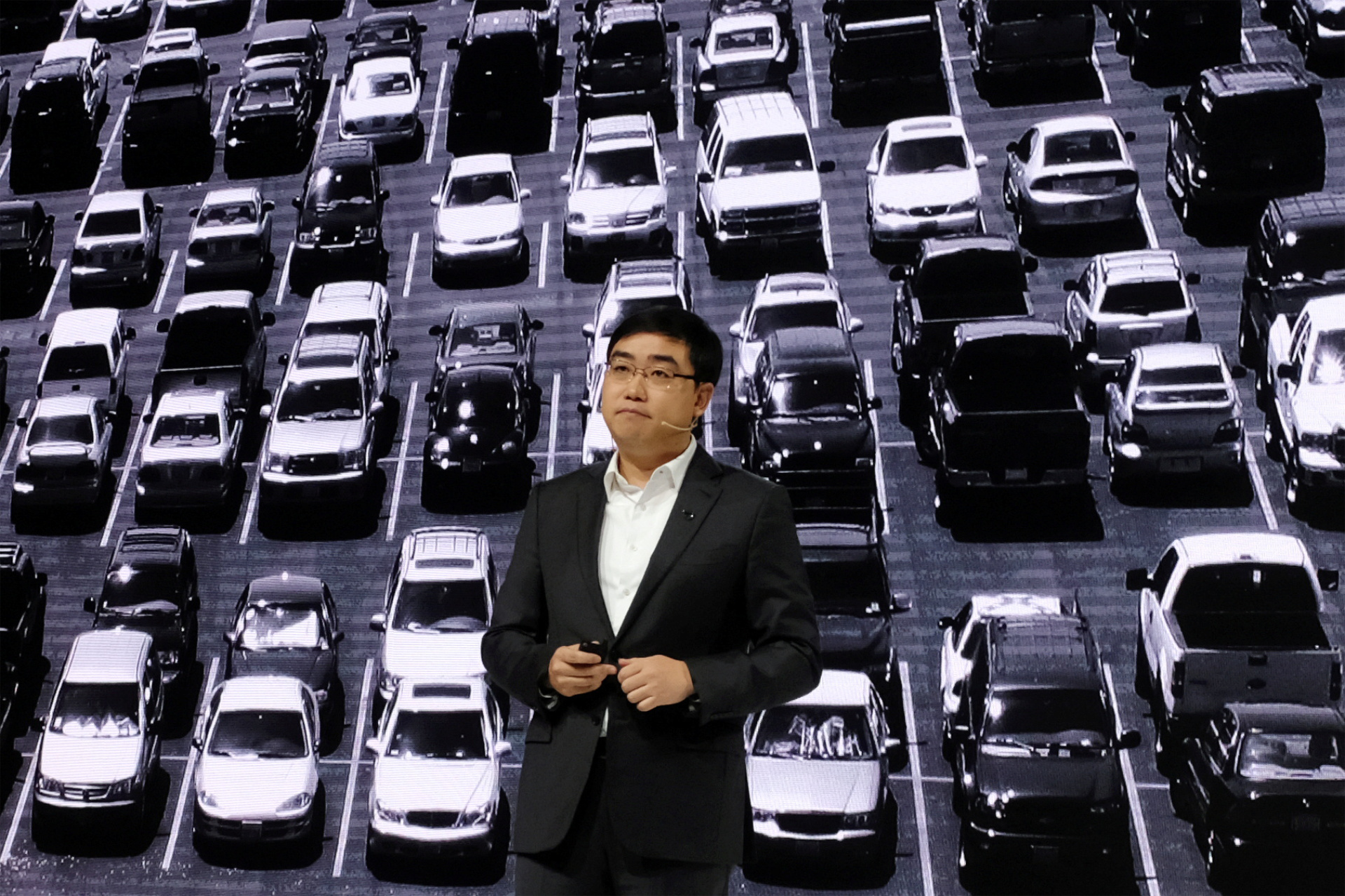 cheng wei, the CEO of Didi Chuxing, in front of an image of cars in a parking lot
